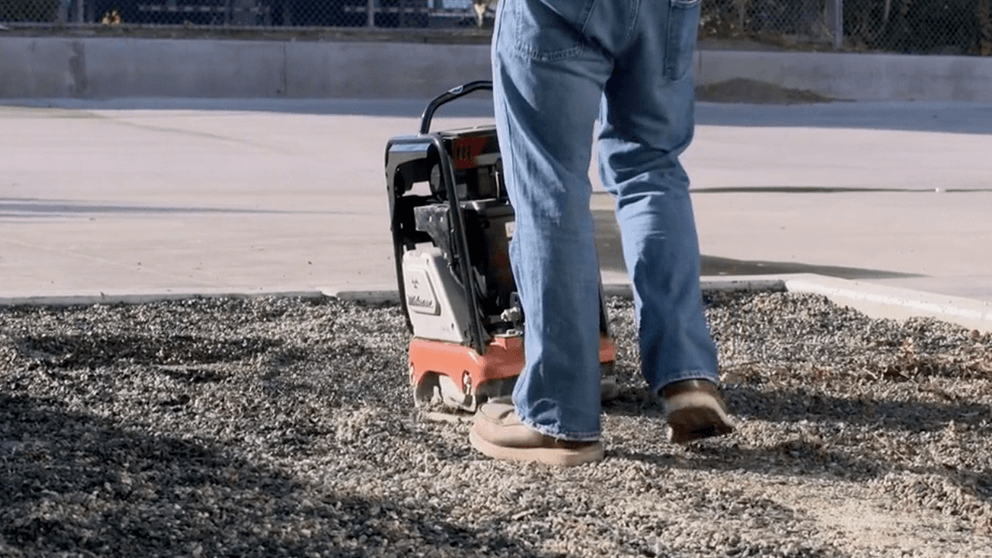 Worker operating battery plate compactor